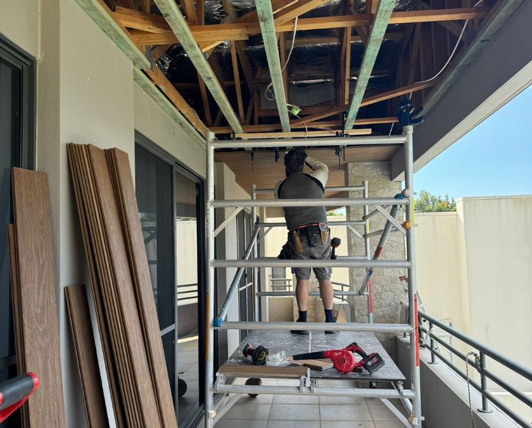 Tradesperson re-sheeting a ceiling from a mobile scaffold