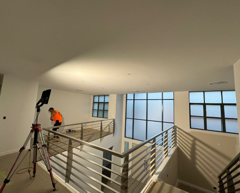 Painter finishing a freshly painted landing in a Brisbane home